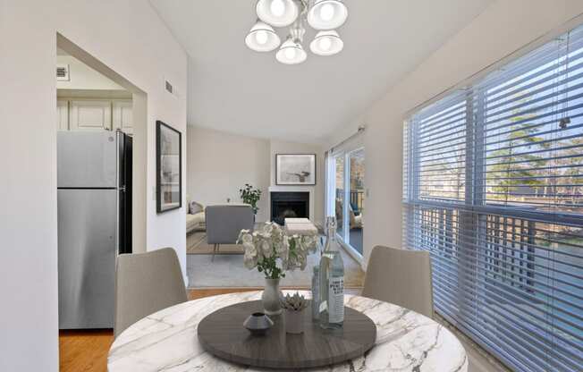 a dining room with a round table with four chairs and a fireplace in the background