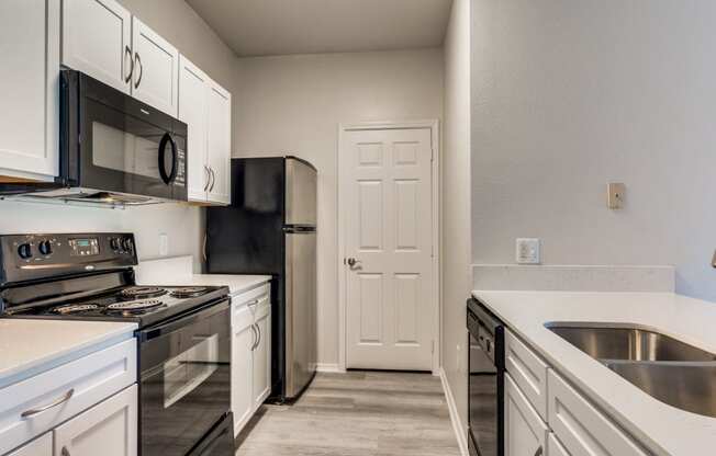 a kitchen with white cabinets and black appliances Arioso apartments located at 3030 Claremont Dr in Grand Prairie, TX