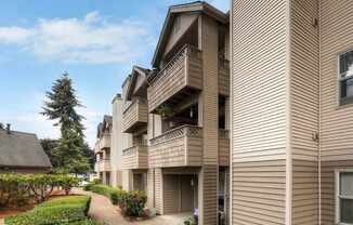 Apartment building with a balcony and a tree in the background.