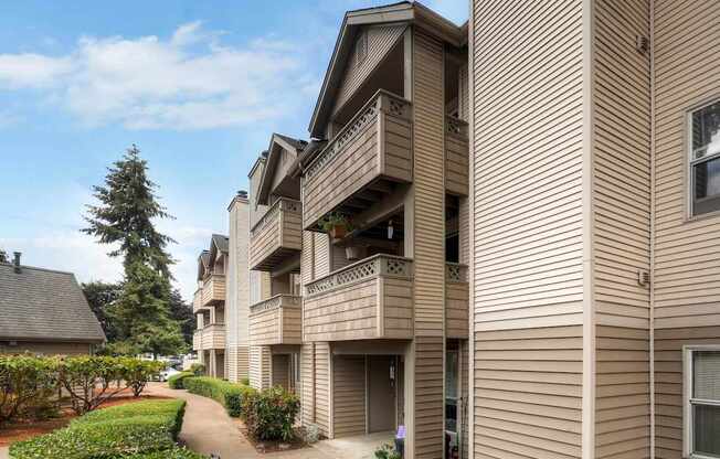 Apartment building with a balcony and a tree in the background.