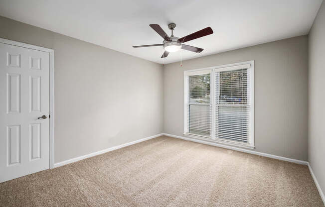 A room with a ceiling fan and a window with blinds.