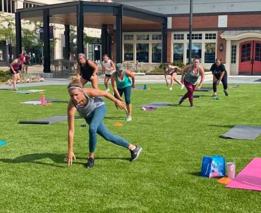 a group of people doing yoga on a lawn in front of a building