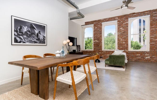 a dining room with a wooden table and chairs and a living room with exposed brick