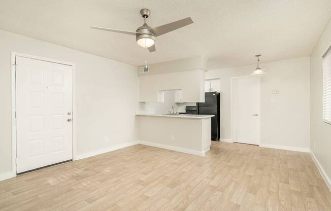 A room with a ceiling fan and wooden flooring.