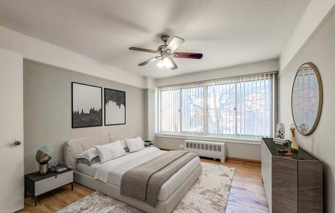 a bedroom with a large window and a ceiling fan