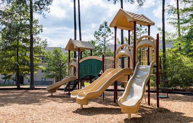 A playground with a yellow slide and a green roofed structure.
