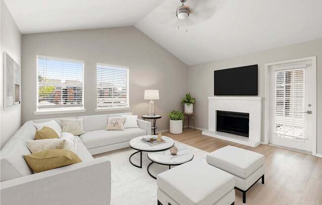 Bright living room with vaulted ceiling, fireplace, large windows, and soft neutral finishes.