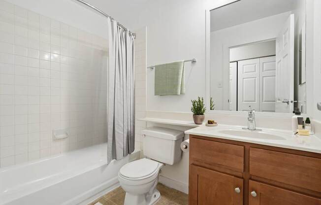 A white toilet sits next to a white bathtub in a bathroom.