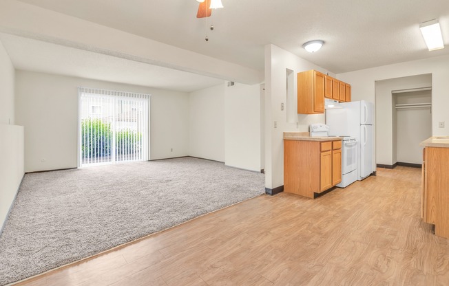 A room with a kitchenette and a sliding glass door leading to a balcony.
