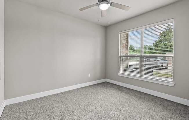 an empty room with a window and a ceiling fan