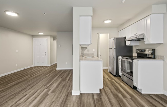 an empty kitchen with white cabinets and a stainless steel stove and refrigerator