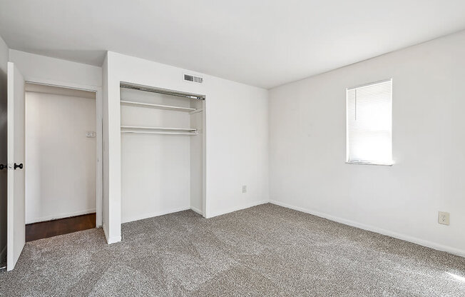 an empty room with a closet and a window