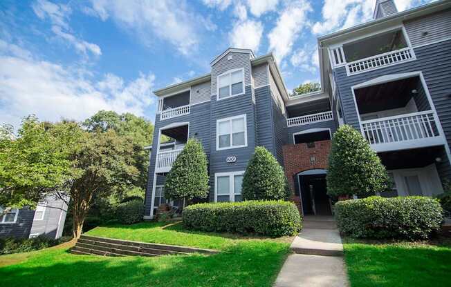 A large grey apartment building with a green lawn in front.