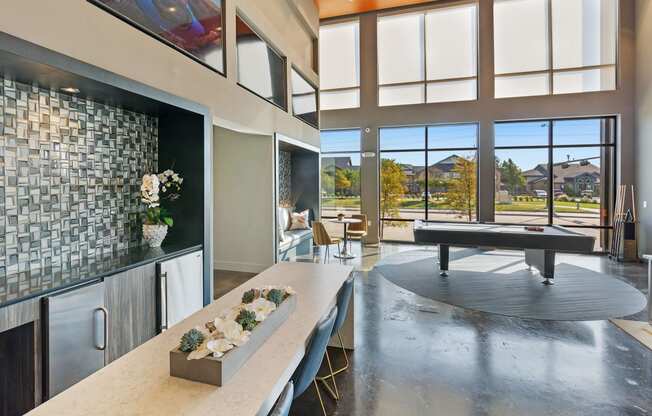 a living room with a ping pong table and a kitchen with a large window