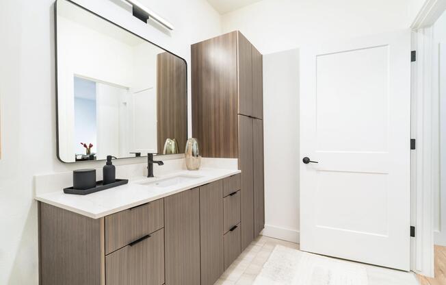 This bathroom showcases a sleek vanity with ample drawer and cabinet storage, along with a tall linen cabinet for added organization.
