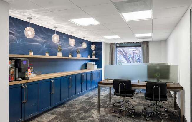 A room with a desk, chairs and a blue wall with a mural.