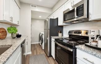 a kitchen with white cabinetry and black appliances  at Lake Johnson Mews, Raleigh