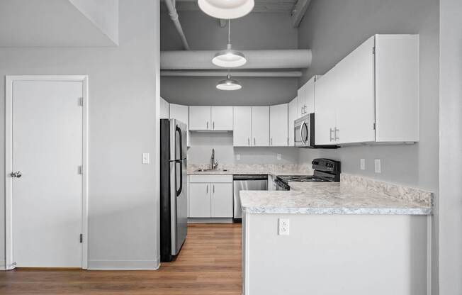 A kitchen with white cabinets and a marble countertop.