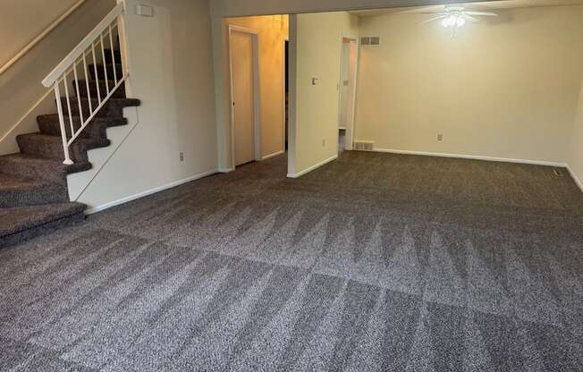 A room with a carpeted floor and a staircase.