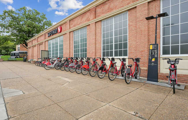 A row of red bikes are parked outside a building with a sign that says