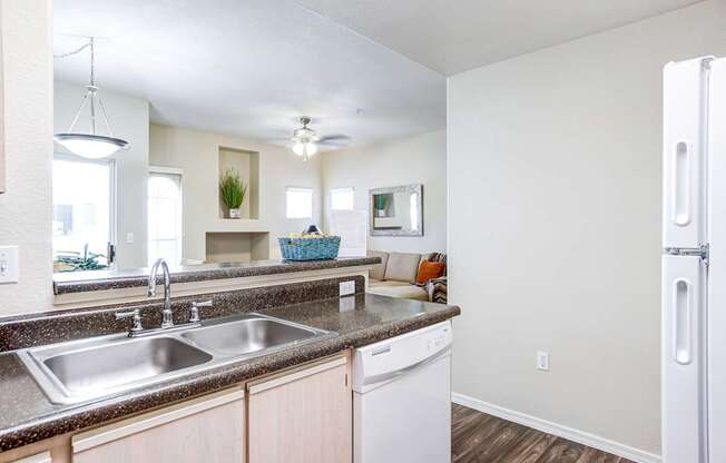 A kitchen with a white fridge and a stainless steel sink.