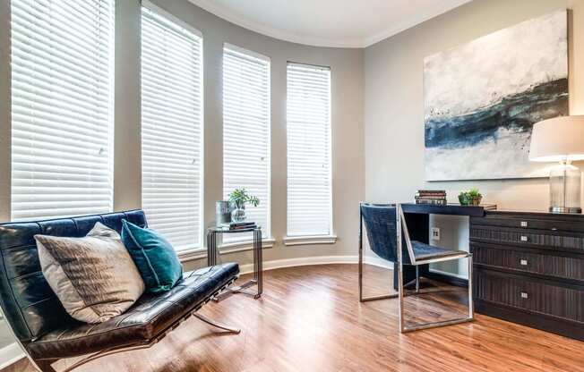 Living room with a leather couch and a desk and three windows at Vintage Park Apartments, Houston, TX