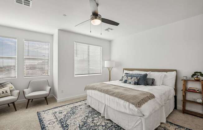 A bedroom with a large bed, a chair, and a ceiling fan.