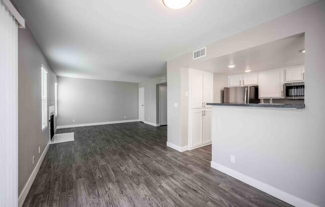 a renovated living room and kitchen with white walls and wood floors