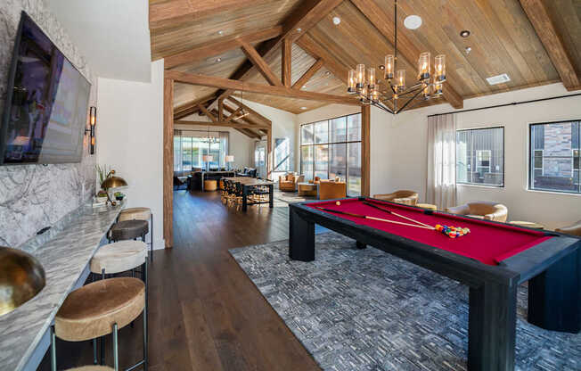 A billiard table is in the middle of a room with a wooden ceiling.