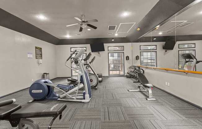A gym with a variety of equipment including treadmills, elliptical machines, and weight machines.