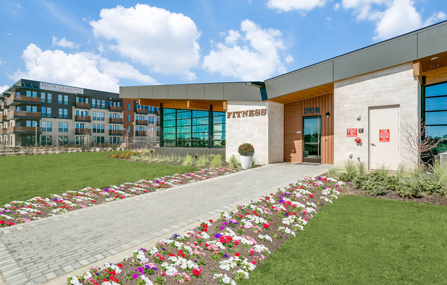 A gym building with a flower bed in front.