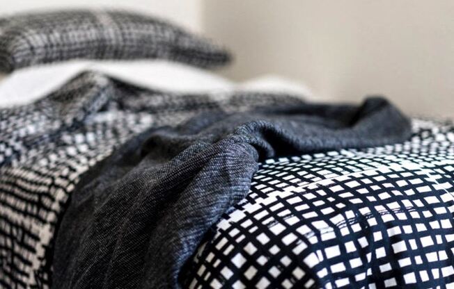 a bed with a checkered comforter and a black and white blanket