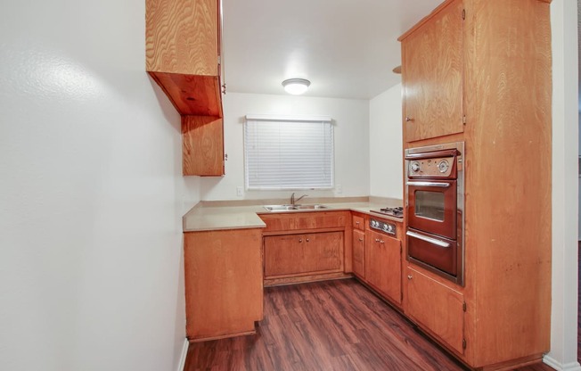 Kitchen with stainless steel Microwave oven,  gas cooktop, quartz countertops, wood kitchen cabinets, and wood-inspired flooring