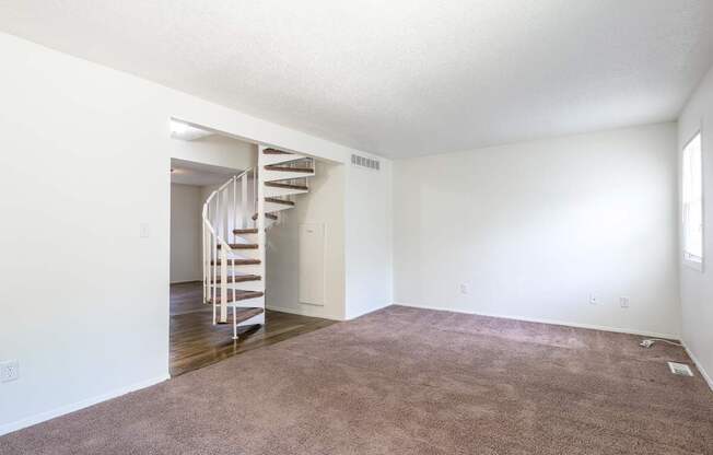 A room with a carpeted floor and a spiral staircase at Spring Creek Townhomes Apartments, Springfield, IL 62702