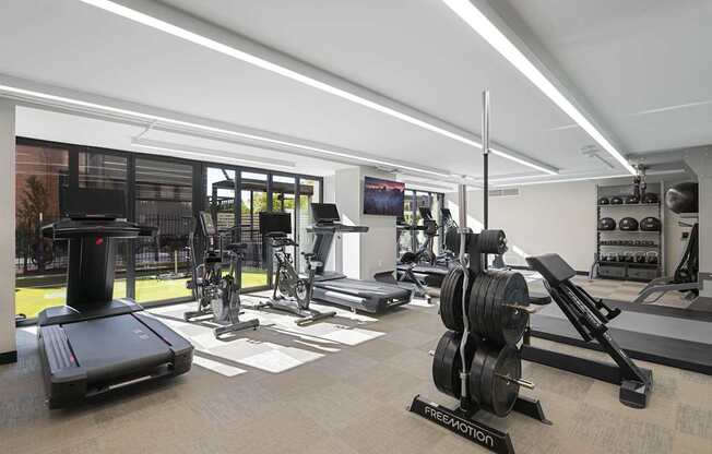 a gym with weights and cardio equipment on the floor and windows