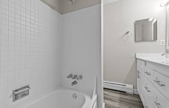 a white bathroom with a tub and a sink and a mirror