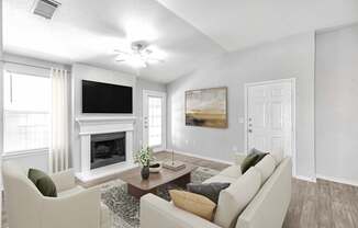 A living room with a fireplace, a television, and a painting.
