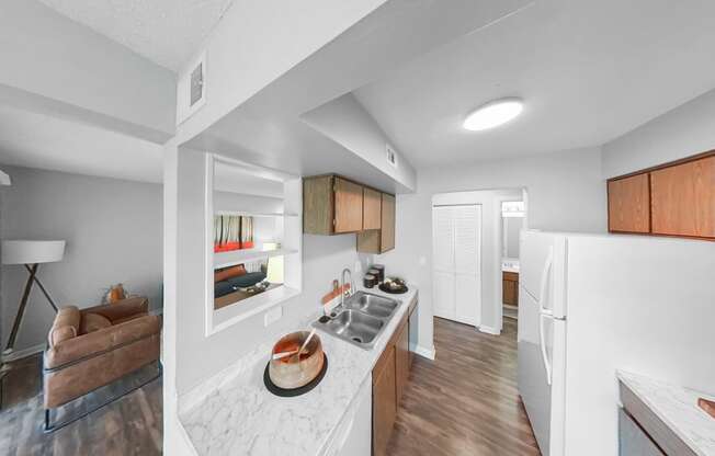 the kitchen and living room of an apartment with white walls and wood flooring