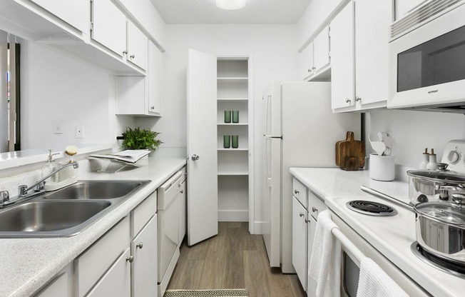 a kitchen with white cabinets and a stainless steel sink