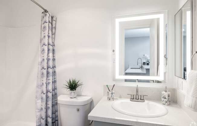 a white bathroom with a mirror and a sink and a toilet