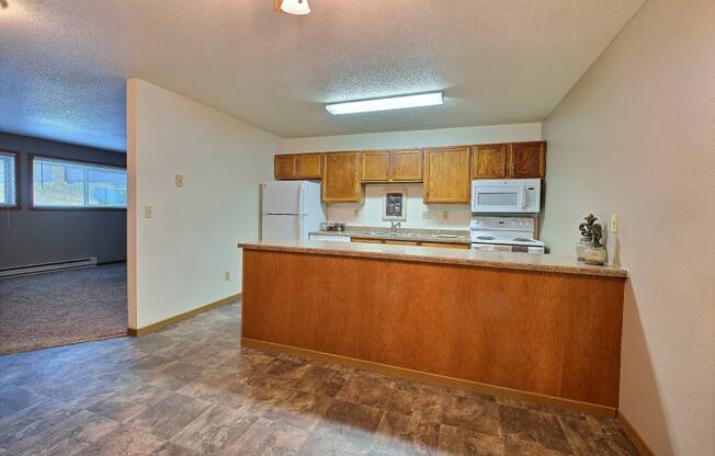 an empty kitchen with wood cabinets and a counter top. Fargo, ND Kennedy Apartments