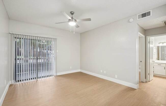 A room with a ceiling fan and a window with blinds.