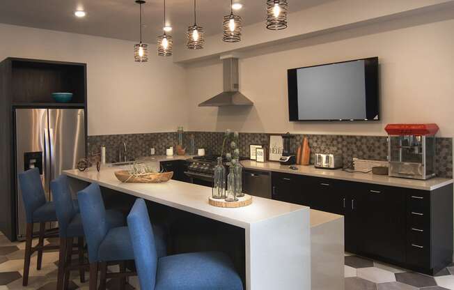 a kitchen with a long island with blue chairs and a television