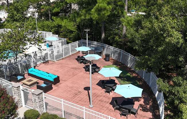 A patio with tables and chairs surrounded by a fence.