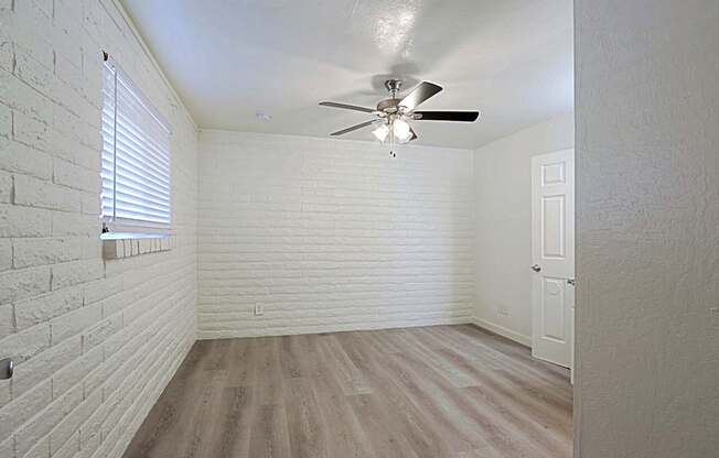 A room with a ceiling fan and a window with blinds.