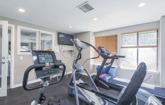 the gym has cardio equipment and a flat screen tv