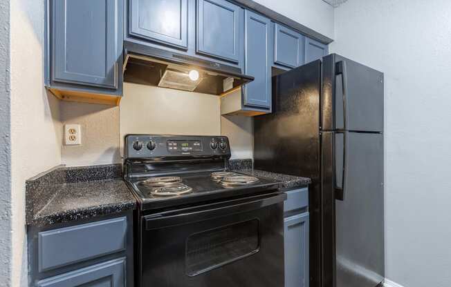 Whitney Manor Apartments in Gretna, LA photo of  a kitchen with black appliances and blue cabinets