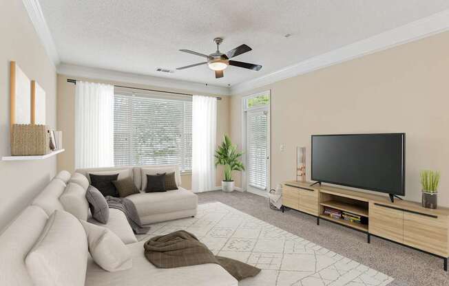 A living room with a couch, a television, and a ceiling fan.