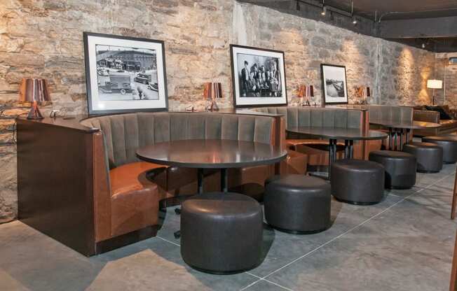 Club Room with Quarter-Circle Booths Around Circle Tables In Front of Exposed Brick Wall at 700 Central Apartments, MN, 55414