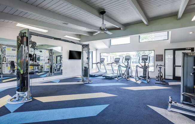 A gym with a variety of equipment including treadmills, weights, and exercise bikes.